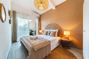 Ein Schlafzimmer mit einem großen Bett, einer Nachttischlampe und einem Fenster mit Vorhängen.
