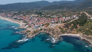 Luftaufnahme einer Küstenstadt mit Strand, Häusern und umliegenden Hügeln.
