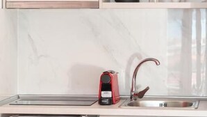 Eine kompakte Küche mit einem eingebauten Kühlschrank, einer Spüle und einer Kaffeemaschine auf der Arbeitsplatte.
