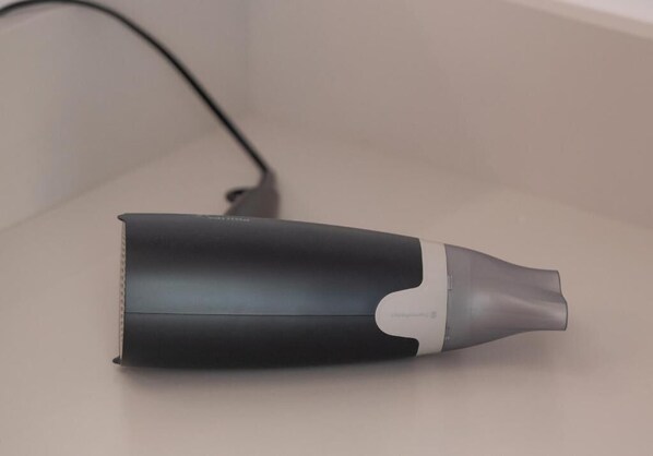 A black and gray cylindrical object with a white accent, possibly a portable device, on a plain surface.