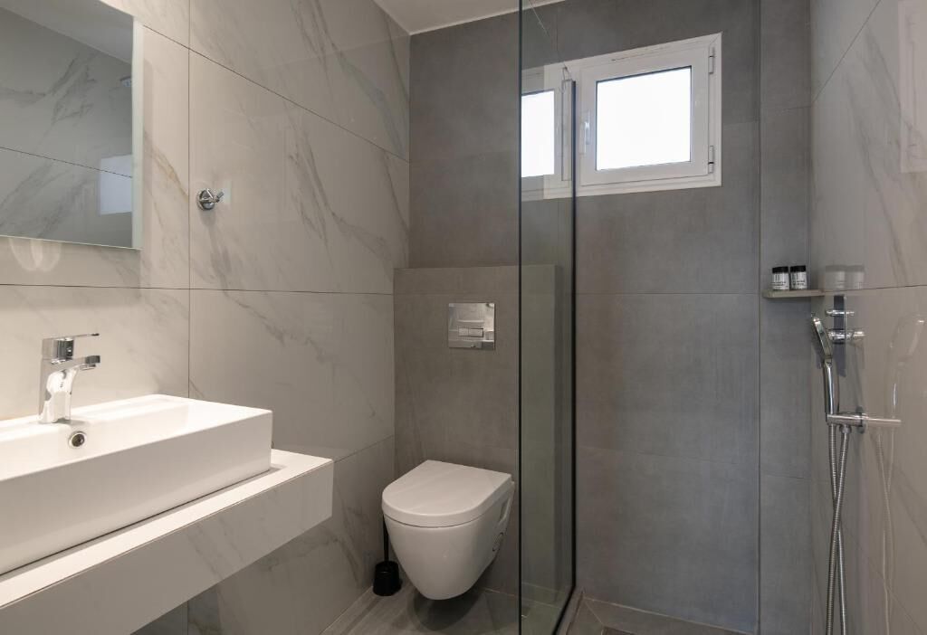 Une salle de bain moderne avec une douche à parois de verre, un lavabo blanc et des toilettes.