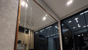 Un espejo grande con marco dorado que refleja un interior moderno con comedor, cama y escalera.