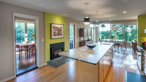 A modern kitchen with a large island, wooden flooring, and a view of the outdoors. - 1 of a Kind: Modern Architecture, Natural Beauty, Walk to Amherst College (Amherst)