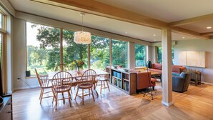 A spacious living area with a dining table, chairs, and a bookshelf. - 1 of a Kind: Modern Architecture, Natural Beauty, Walk to Amherst College (Amherst)