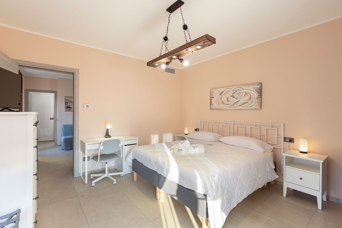 Ein Schlafzimmer mit einem Bett, Nachttischen, einem Schreibtisch und einem Sessel.