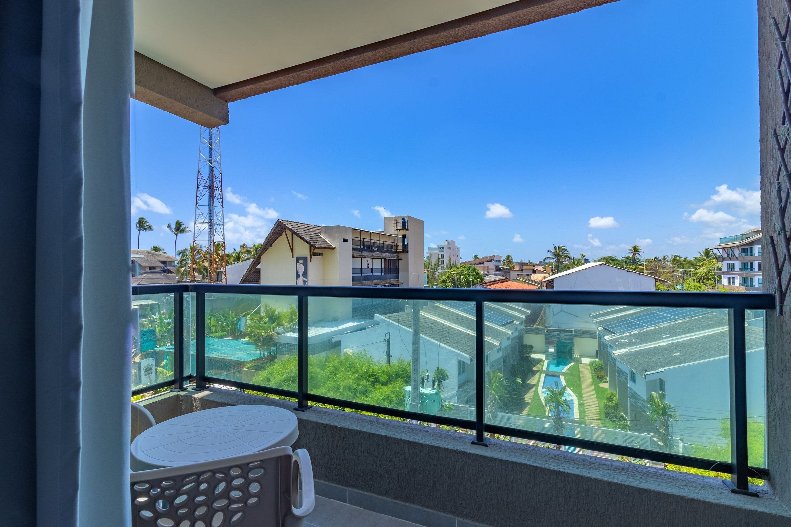 A balcony with a glass railing, a table, and a chair.