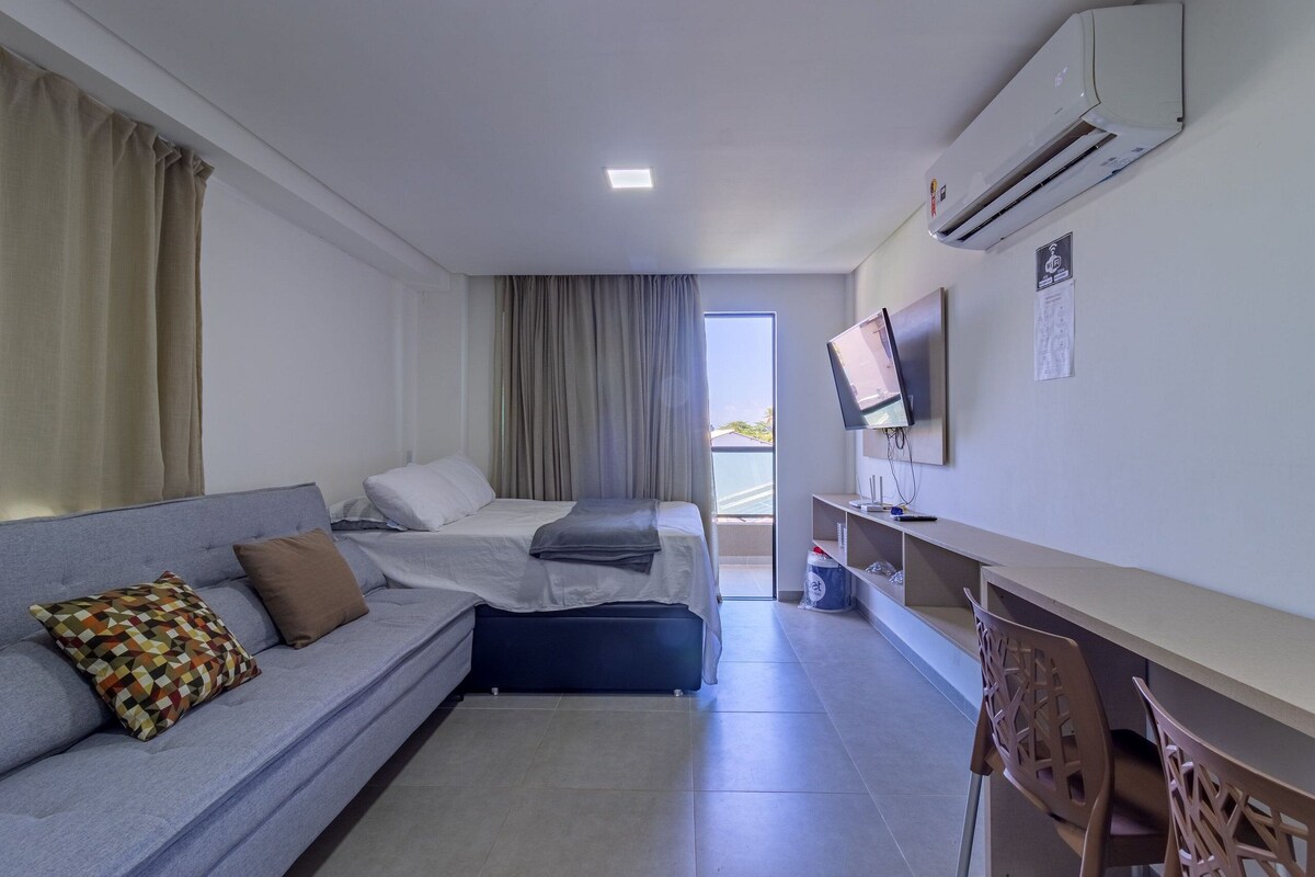 A modern hotel room with a sofa, a bed, a desk, and a television.