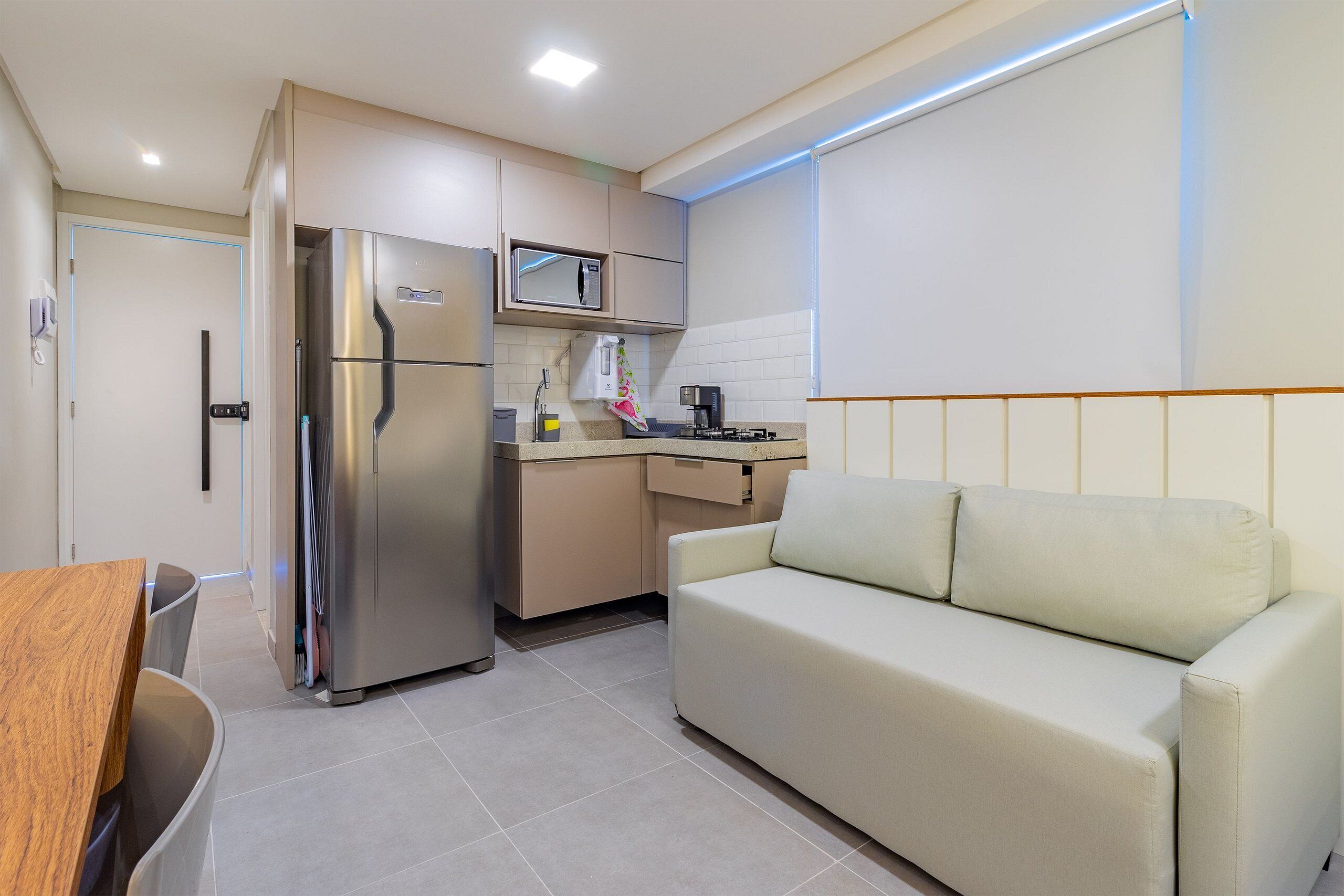 Une petite cuisine équipée comprenant un réfrigérateur, un four à micro-ondes et une cuisinière. On y trouve également un canapé et une table en bois avec des chaises.