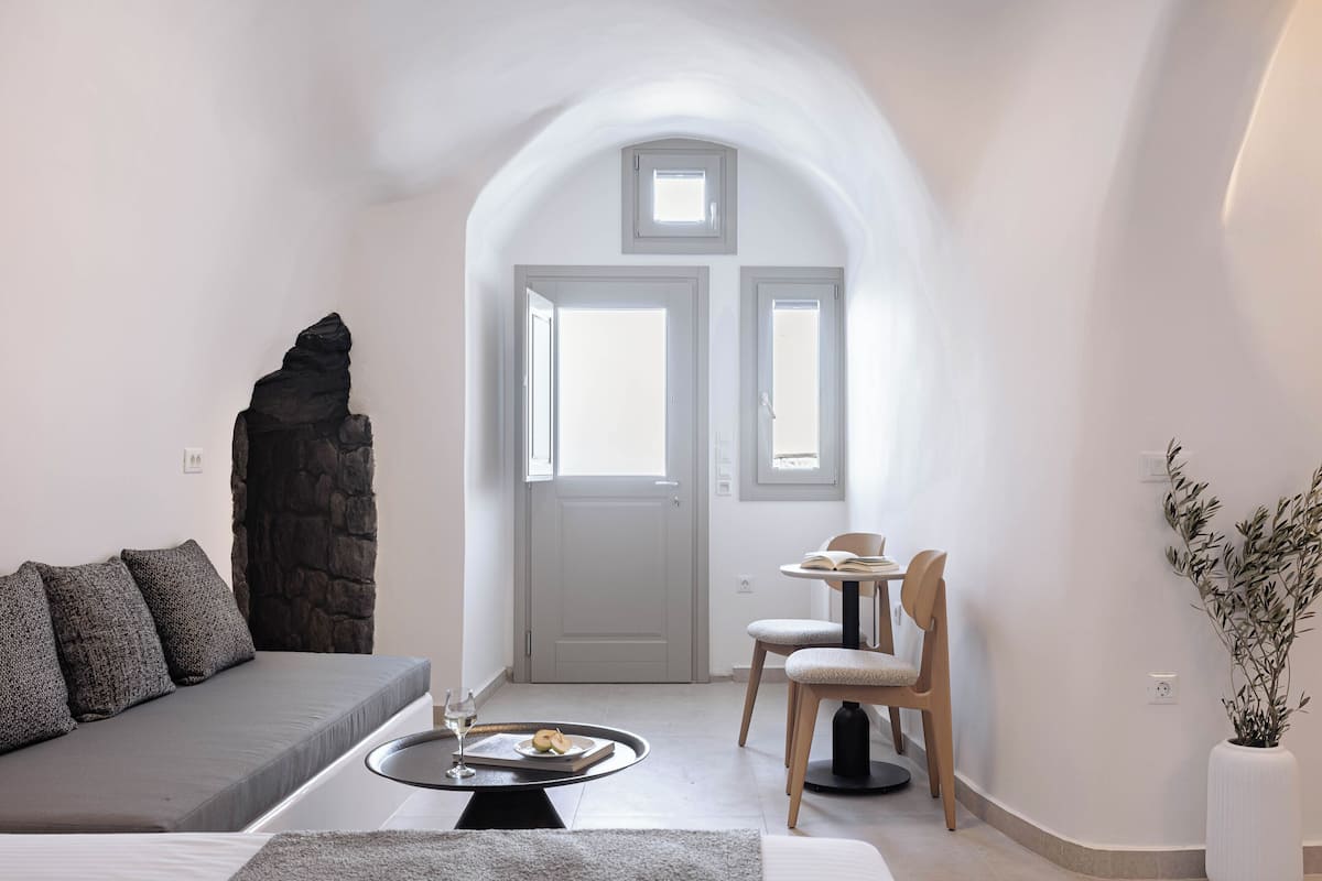 A modern living room with a grey sofa, a dining table with chairs, and a stone accent wall.