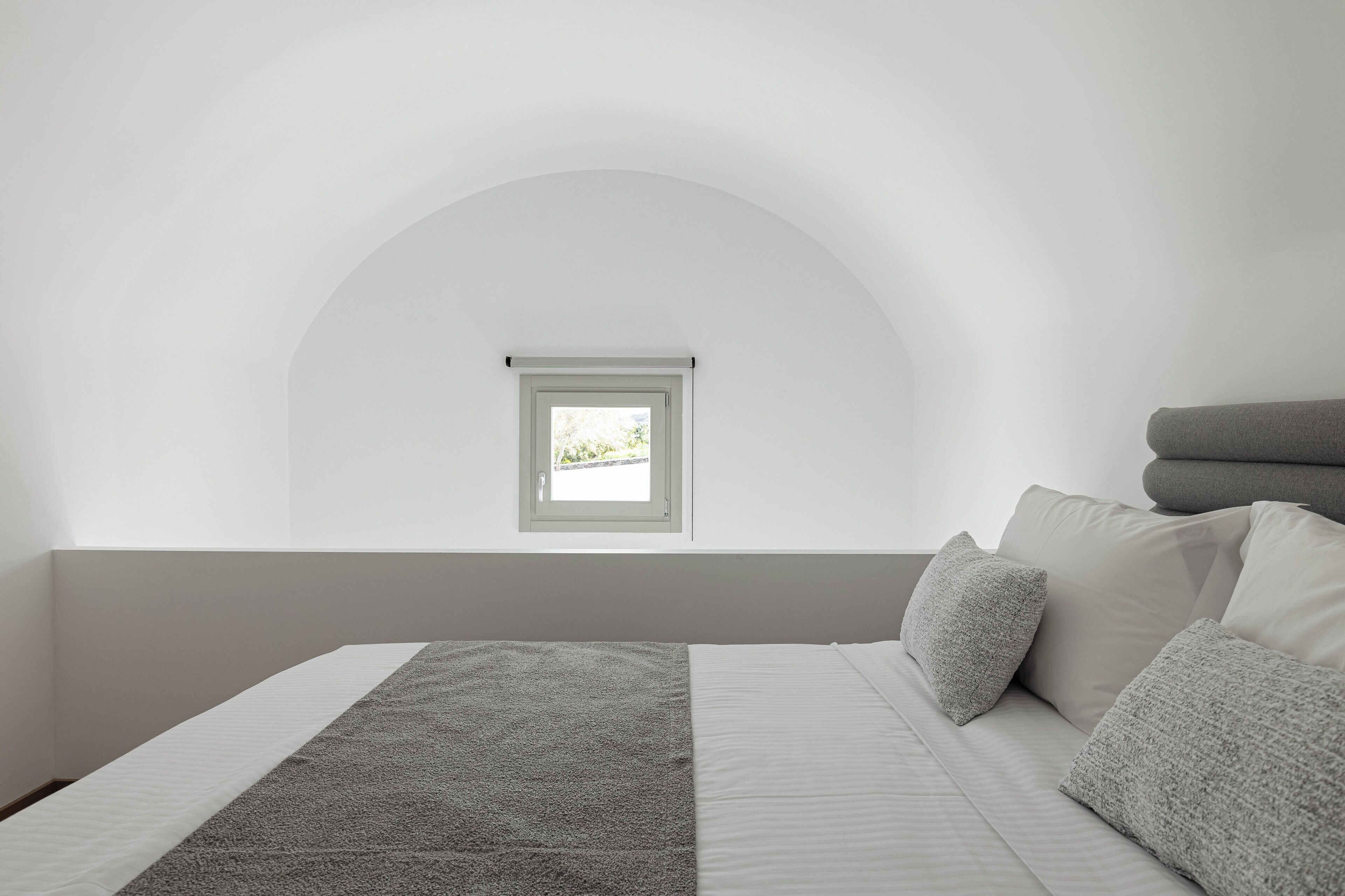 A bedroom with a bed, a window, and a view of the outdoors.