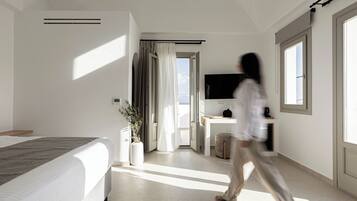 Habitación de hotel moderna con una cama grande, televisor, escritorio y vistas al exterior.