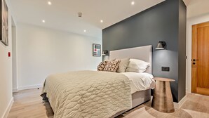 Ein modernes Schlafzimmer mit einem großen Bett, einem Nachttisch und einer Wandlampe.
