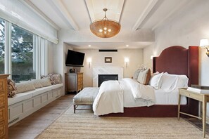 A bedroom with a large bed, a television, a fireplace, and a window seat. - Montecito Luxury | Pickleball, Putting Green, Media Lounge, Hot tub & EV Charger (Montecito)