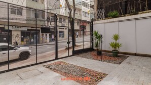Un patio con cerramiento metálico, plantas en macetas y un área pavimentada con piedras.