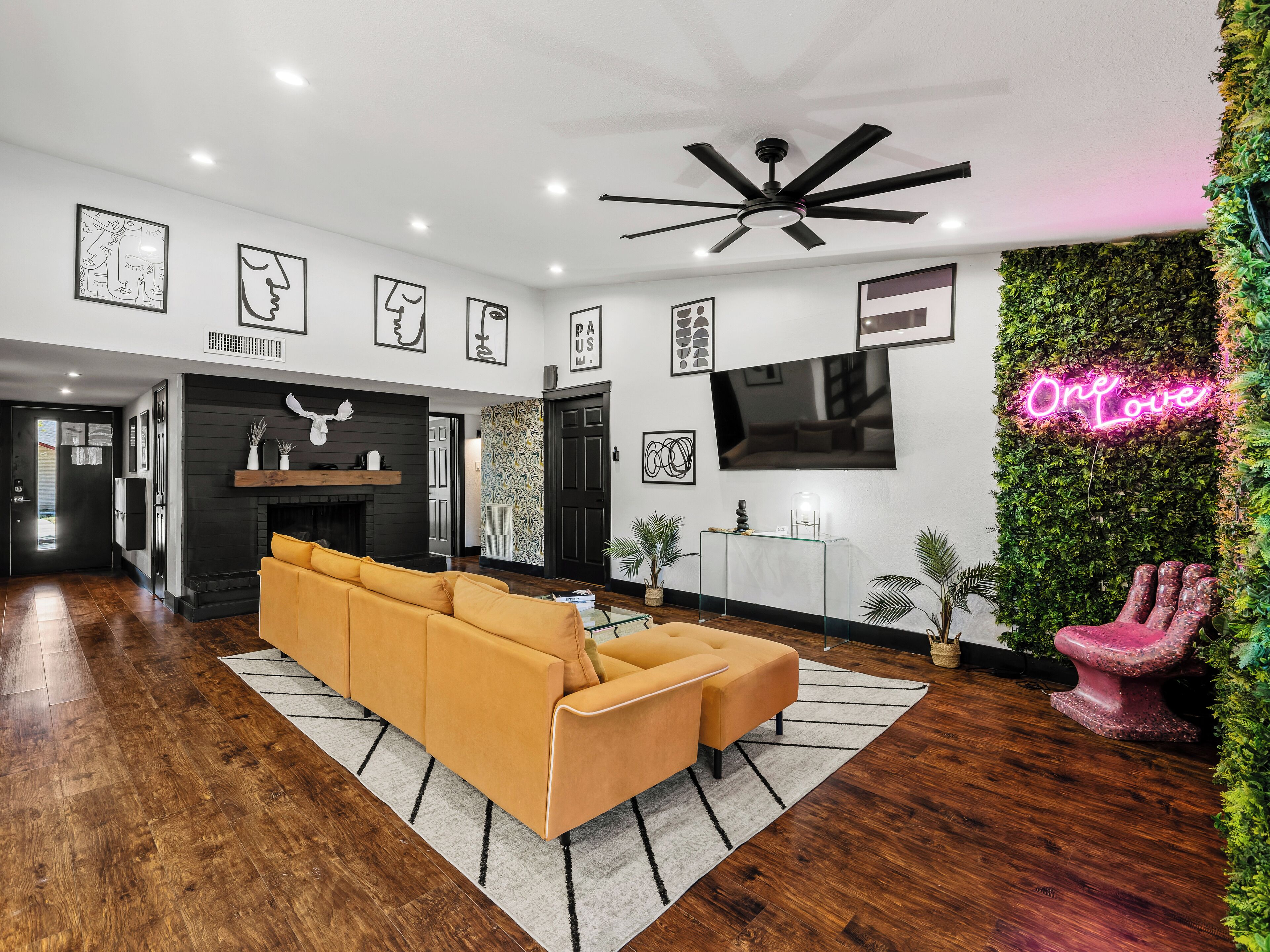 A modern living room with a sofa, a fireplace, and a TV mounted on the wall.