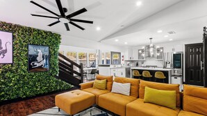 A modern living room with a sectional sofa, a glass coffee table, and a ceiling fan. - Stunning Carrolton Castle with 4 Bedrooms + Pool + Media Room (Carrollton)
