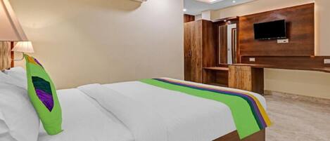 Habitación de hotel con cama, ventilador de techo, equipo de aire acondicionado, televisor montado en la pared y un armario de madera.