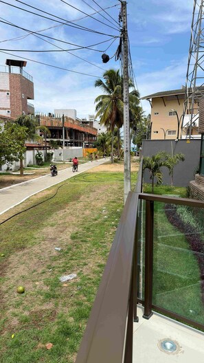 A residential area with a clear sky, a street with a few vehicles, and a building under construction. - Porto Ibiza (Ipojuca)