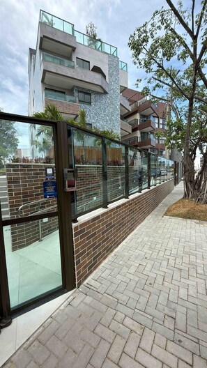 Un edificio moderno con entrada de vidrio, paredes de ladrillo y un camino pavimentado.