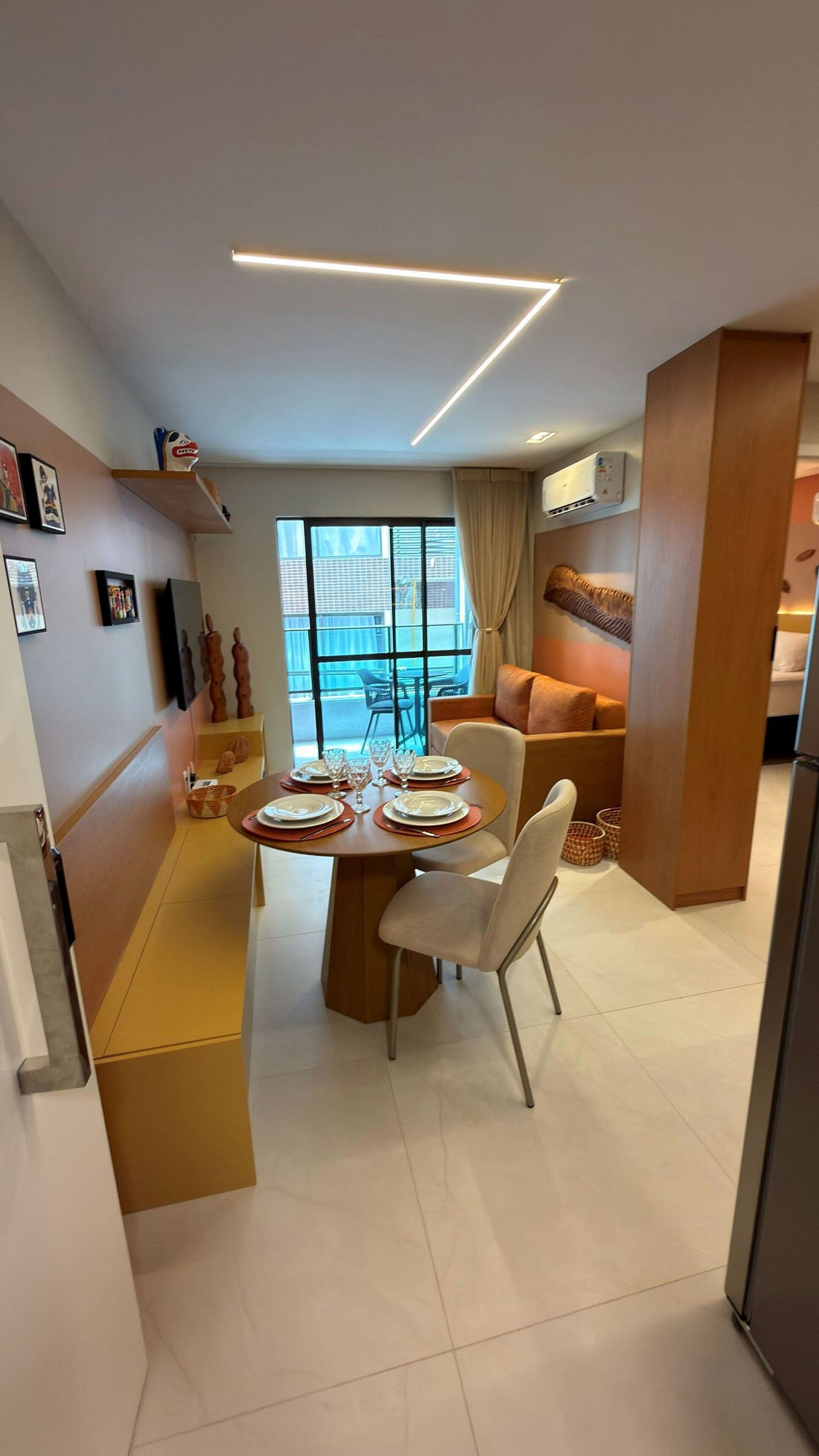 Un espace de repas moderne avec une table dressée pour deux personnes, un canapé et une vue sur l’extérieur.