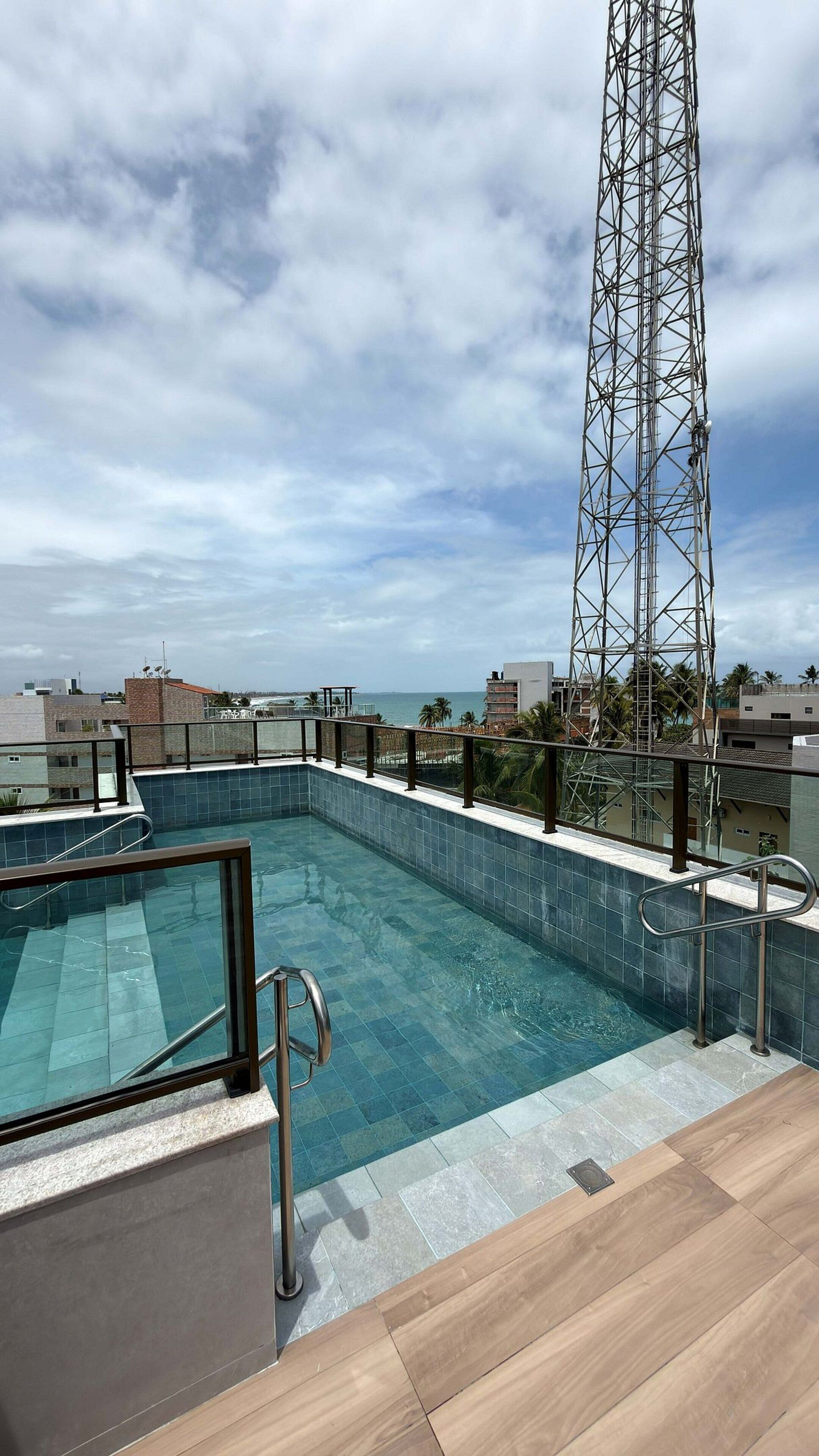 Une piscine sur le toit offrant une vue sur l’océan et une haute tour de télécommunications.