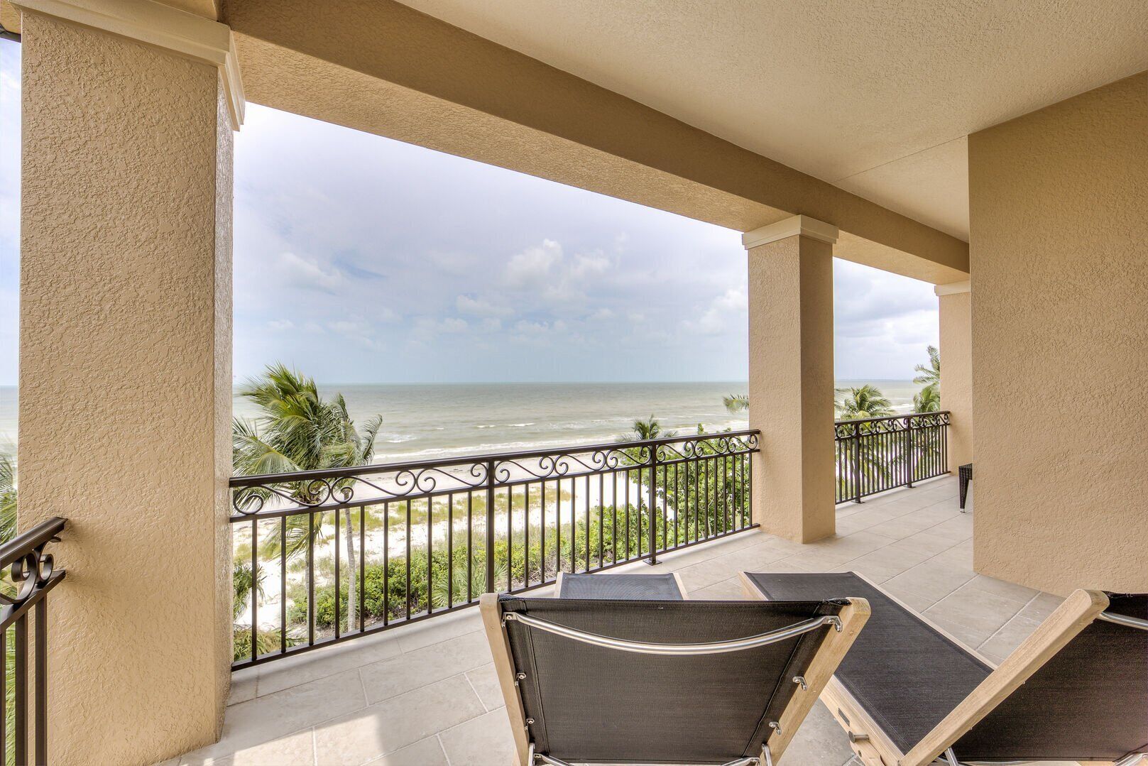 A balcony with a view of the ocean, featuring a chair and a table.