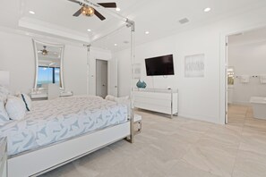 A modern bedroom with a bed, bedside tables, a ceiling fan, a TV, and a bathroom with a bathtub and towel rack. - 🌴Luxury Beachfront | Private Pool | Elevator | Stunning Views | Blue Paradise🌴 (Fort Myers Beach)