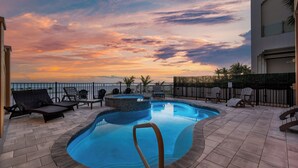 Une piscine avec des chaises longues, un jacuzzi et une vue sur le coucher de soleil.