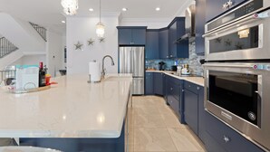 Une cuisine moderne dotée d’un grand îlot central, d’appareils électroménagers en acier inoxydable et d’une décoration murale en forme d’étoiles.