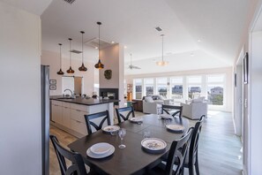 A modern kitchen with a dining area, large windows, and a view of the city. - Gorgeous semi-oceanfront home on the 4x4 beaches w/ swim spa & ocean views! (Carova)