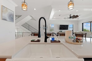 A modern kitchen with a large island, stainless steel appliances, and a dining area with a view.
