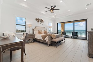 A spacious bedroom with a large bed, a desk, and a view of the ocean. - 🌅Gulf Front Stunner | Private Pool + Spa | Elevator | Sunset Siesta🌅 (Fort Myers Beach)