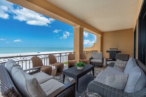 A balcony with wicker furniture, a table with a plant, and a view of the ocean. - 🌅Gulf Front Stunner | Private Pool + Spa | Elevator | Sunset Siesta🌅 (Fort Myers Beach)
