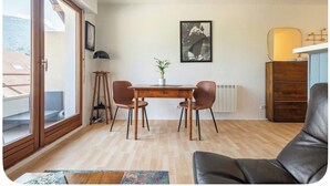 Un'area pranzo con tavolo e sedie, una pianta in vaso e un quadro appeso al muro.