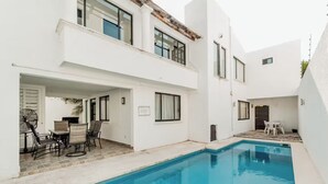 Um edifício moderno de dois andares com piscina, área de estar ao ar livre e um pátio.
