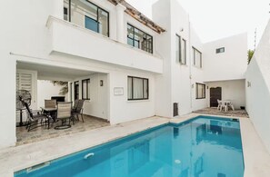 A modern two-story building with a swimming pool, outdoor seating, and a patio area. - Casa de lujo en Cancún con alberca privada y 4 recámaras (Cancún)