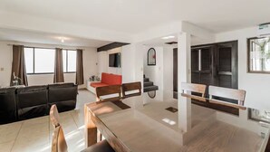Uma sala de estar moderna com uma mesa de jantar de madeira, um sofá vermelho e um sofá de couro preto.
