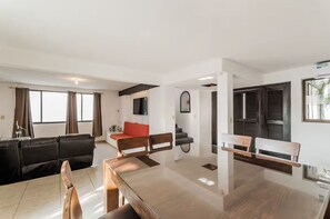 A modern living room with a wooden dining table, a red sofa, and a black leather couch. - Casa de lujo en Cancún con alberca privada y 4 recámaras (Cancún)