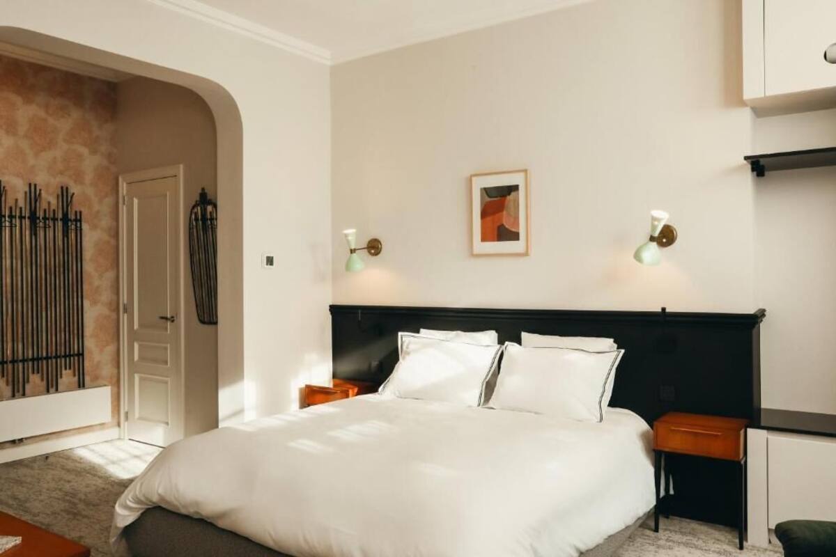 Ein Hotelzimmer mit einem großen Bett, zwei Nachttischen, einem Schrank und einem gerahmten Bild an der Wand.