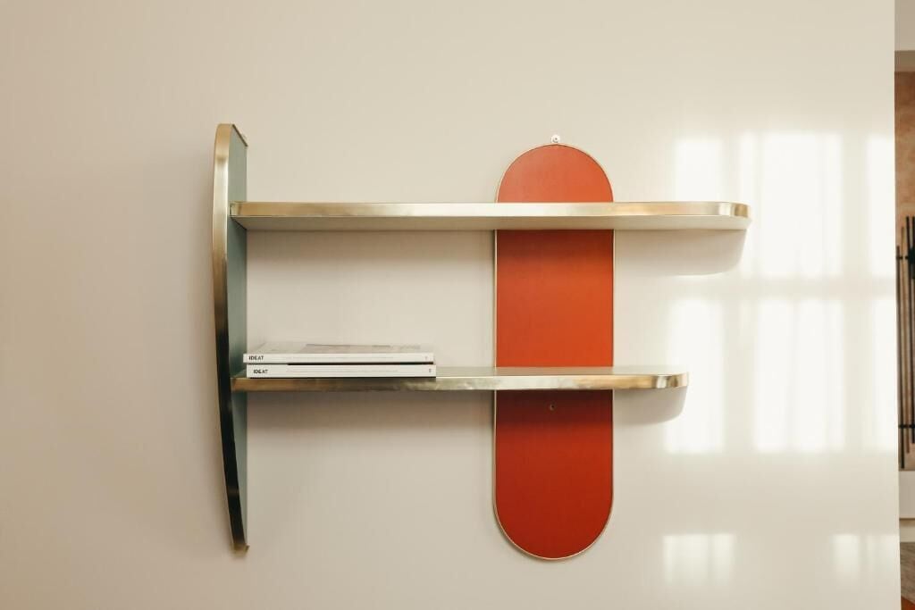 A wall-mounted shelf with a red object and two books.
