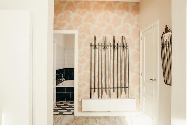 A bathroom with a black and white checkered floor, a white bathtub, and a wall-mounted radiator. - La Villa Maurice (Brussels)