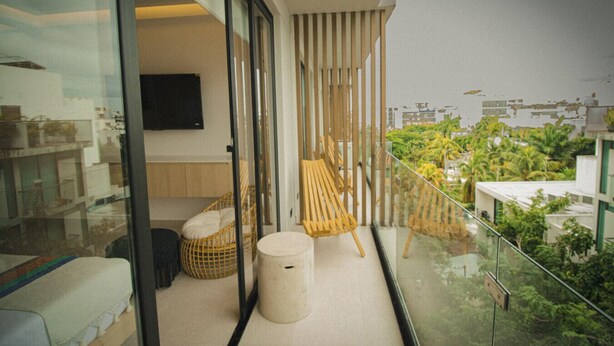 Een balkon met een bank, een stoel en een kleintje tafeltje.