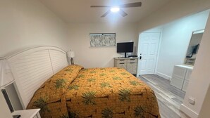 A bedroom with a bed, a ceiling fan, a TV, a dresser, and a door. - #216 Polynesian - WALK 2 PIER PARK you and beach (Upper Grand Lagoon)
