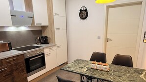 Una cucina moderna con mobili bianchi, forno a incasso, macchina del caffè e un tavolo da pranzo con sedie.