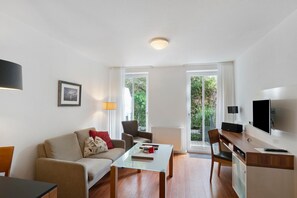 A modern living room with a sofa, a coffee table, a TV, and a dining area with a table and chairs. - 5-Star Comfort Holiday Home Jümmers - 'Antje', Prime Location by the Wadden Sea National Park (Wangerland-Horumersiel)