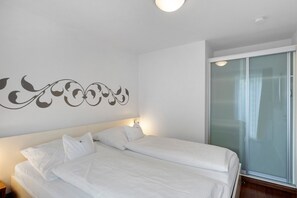 A hotel room with a bed, a nightstand, a wall decoration, and a sliding glass door. - 5-Star Comfort Holiday Home Jümmers - 'Antje', Prime Location by the Wadden Sea National Park (Wangerland-Horumersiel)