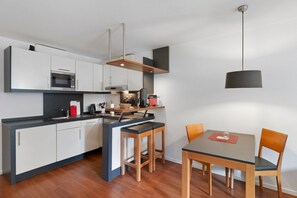 A modern kitchen with a central island, a dining area with a table and chairs, and a pendant light. - 5-Star Comfort Holiday Home Jümmers - 'Antje', Prime Location by the Wadden Sea National Park (Wangerland-Horumersiel)