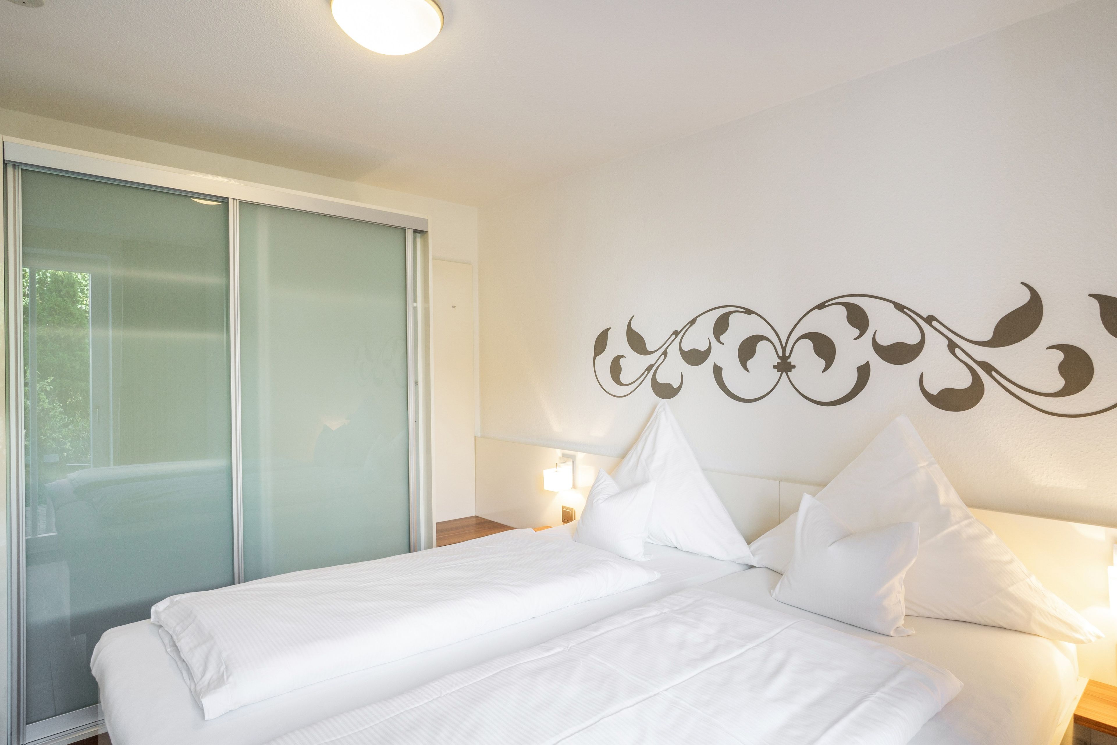 Ein Hotelzimmer mit einem Bett, einem großen Fenster und einer Wanddekoration.