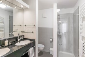 A modern bathroom with two sinks, a toilet, and a glass-enclosed shower.