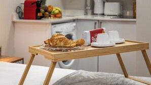 Desayuno con croissant, café y una bandeja sobre la cama.